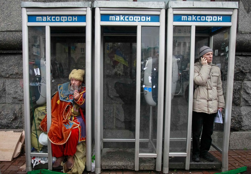 A man dressed in traditional Ukrainian Cossack clothes smokes in a phonebooth during a rally to support EU integration in Kiev